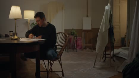 artist working on a drawing in a home studio at night