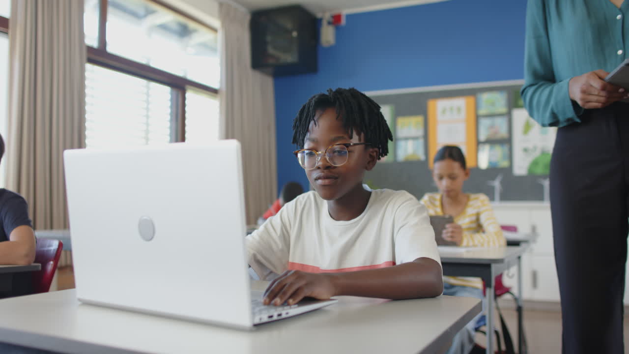 In school, boy using laptop in classroom, focusing on his work