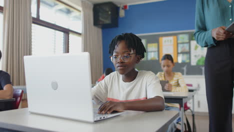 in school, boy using laptop in classroom, focusing on his work