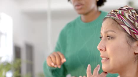 Diverse-business-female-colleagues-in-discussion-using-tablet-in-casual-office-meeting,-slow-motion