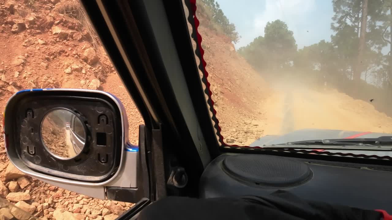 POV jeep ride through Nepal's rugged interior. Slowly driving a dirty road with another jeep driving on front, making a sandcloud