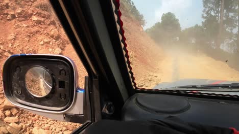 pov jeep ride through nepal's rugged interior. slowly driving a dirty road with another jeep driving on front, making a sandcloud