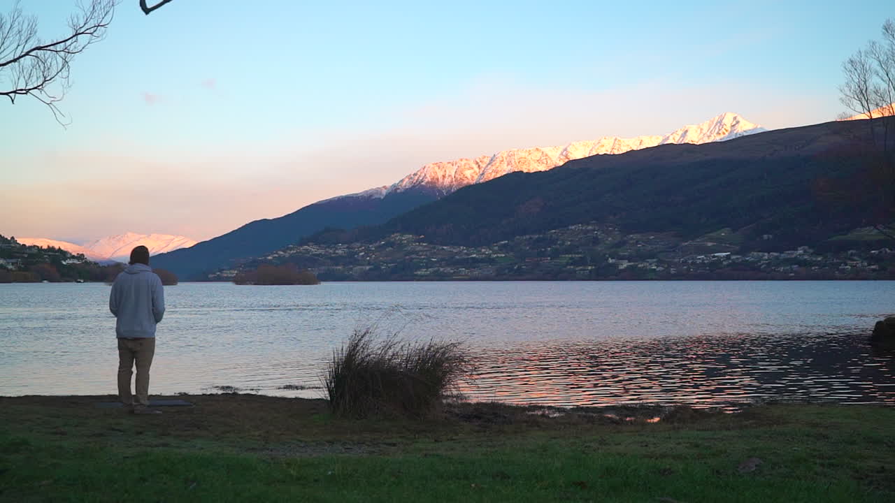hombre disfrutando de la vista de la puesta de sol cayendo sobre las montañas en sus vacaciones