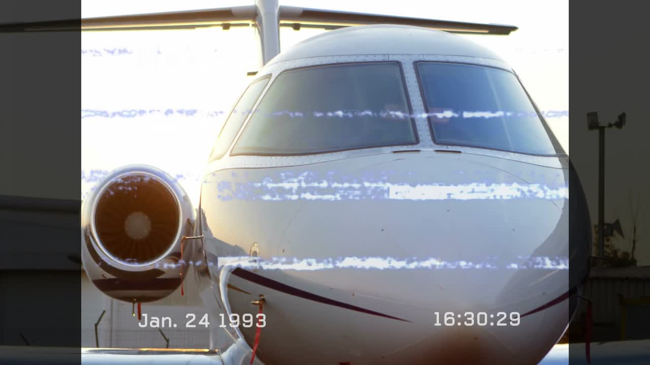 Riflesso del sole che si sposta sulla sezione del muso di un jet privato mentre il rumore VHS svanisce per rivelare i dettagli della cabina di pilotaggio.