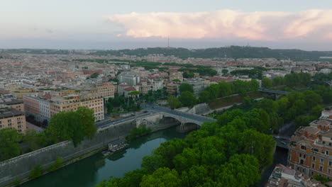 Forwards-fly-above-waterfront.-Tiber-river-lined-by-green-trees-passing-through-city-centre.-Rome,-Italy