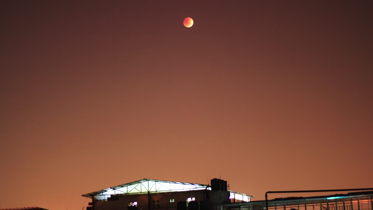Salida de la luna de sangre y time-lapse de transición con un edificio en primer plano y un cielo rojo de fondo.