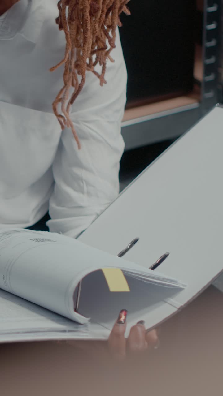 Vertical video: African american woman taking notes on records