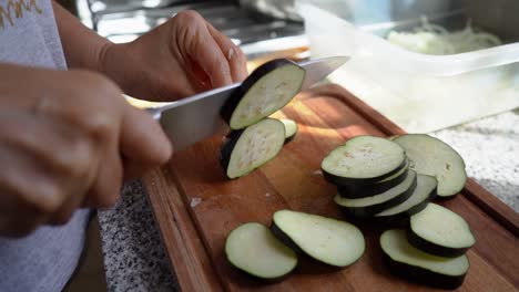 Vista-Recortada-De-Una-Persona-Cortando-Berenjena-Americana-En-La-Cocina