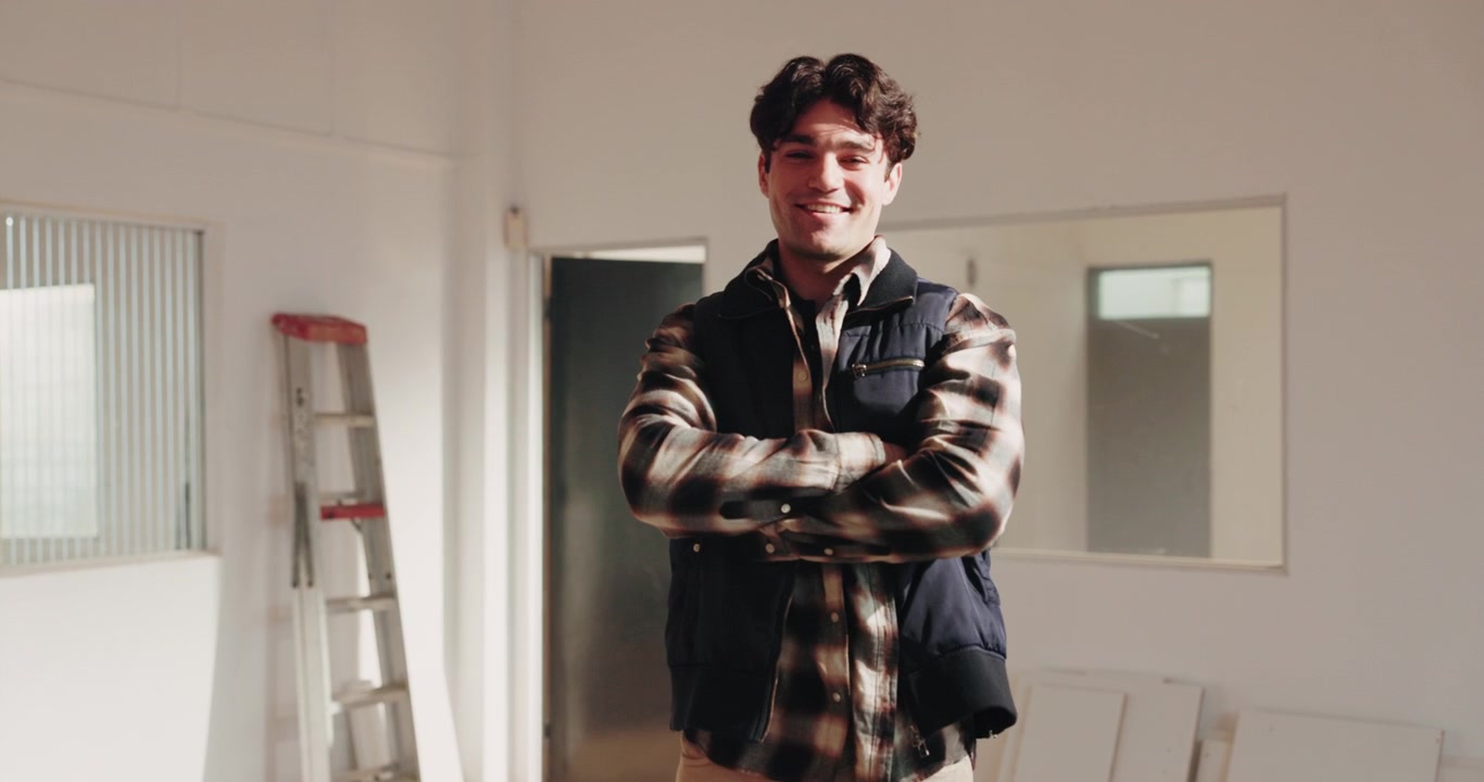 Young Man Standing in Renovating Room with Arms Crossed