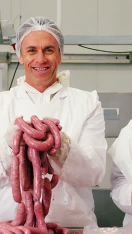 team of butchers holding sausages
