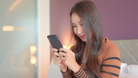 asian woman holding a mobile phone in two hands and typing in group chat, close-up perspective view