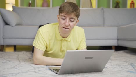 un joven que tiene un colapso nervioso en casa en la computadora portátil.