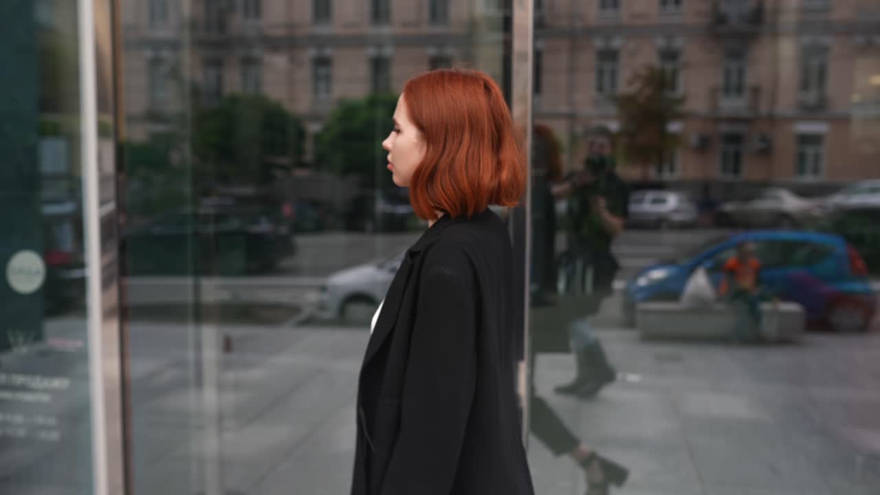 mujer de cabello rojo caminando por una ciudad