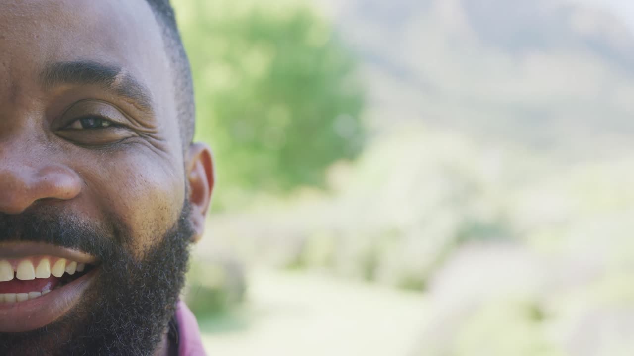 Portrait of happy african american man looking at camera and smiling with copy space, in slow motion