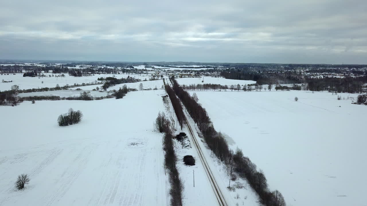 멀리 눈 덮인 도시 풍경이 있는 겨울의 흐린 날 교통 체증 없이 눈 덮인 도로 위를 천천히 앞으로 날아갑니다.