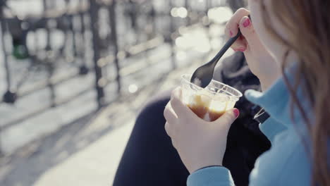 Close-up-of-little-girl-with-blue-jumper-nail-polish-and-teddy-bear-beside-her-holding-a-sundae-ice-cream-sitting-outdoor-4k