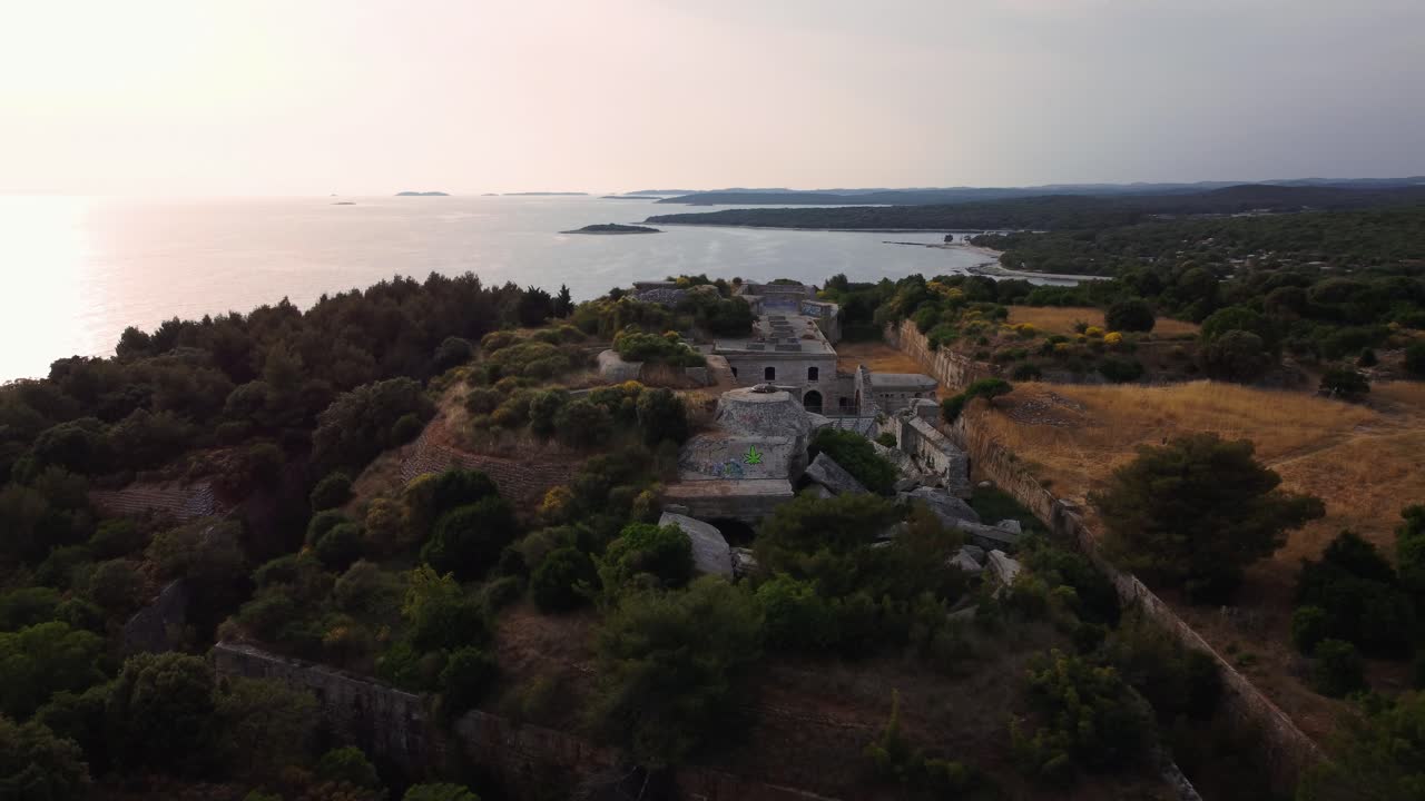 vista aérea cinematográfica círculo de puesta de sol de drones sobre una fortificación histórica de la primera guerra mundial fortaleza junto al mar junto al idílico mar mediterráneo adriático con agua azul y playas escondidas en verano