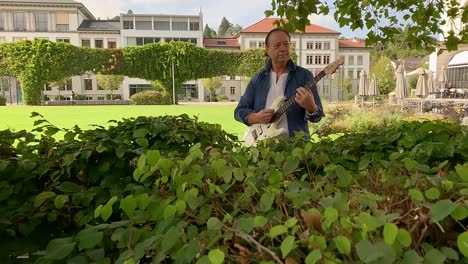 a musician plays a white guitar in the park among the greenery