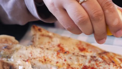 squeezing lemon on grilled fish