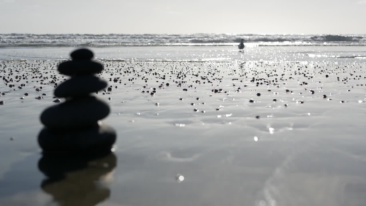 바다 해변에서 바위 균형을 잡고, 바물 파도에 의해 돌이 쌓여, 모래 해변에 있는 자갈의 피라미드.