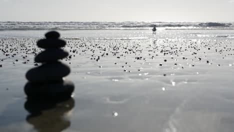 rocas equilibradas en la playa del océano, piedras apiladas por las olas del agua del mar. pirámide de guijarros en la orilla arenosa
