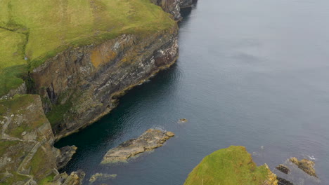 downward angle drone shot of whaligoe haven and the 250ft cliffs overlooking the north sea in scotland