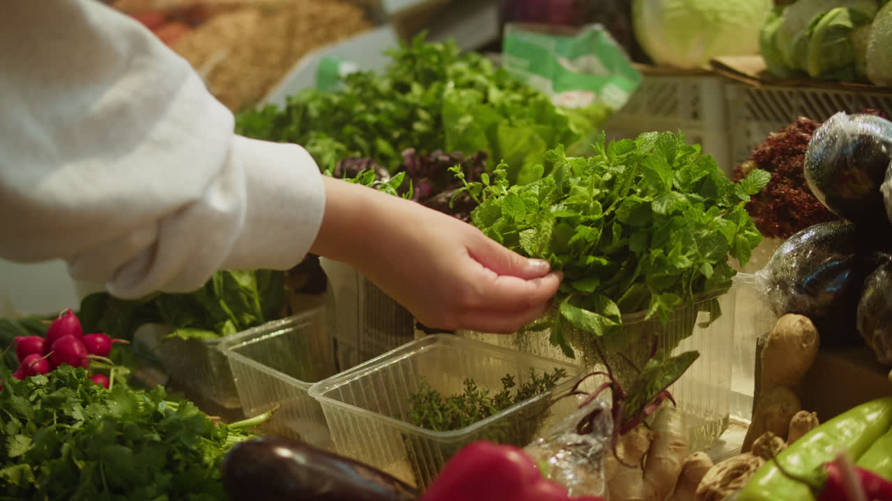 Customer's Hand Selecting Fresh Mint at a Produce Market