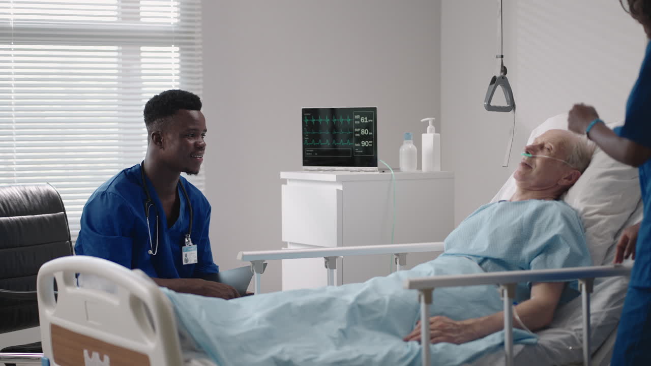 equipo médico étnico africano al lado de la cama de un paciente de edad avanzada. los proveedores de atención médica monitorean los signos vitales de un paciente de edad avanzada del hospital.