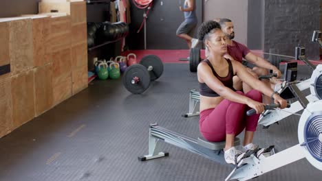 diversas clases de acondicionamiento físico en grupo entrenando duro en máquinas de remo en el gimnasio, en cámara lenta
