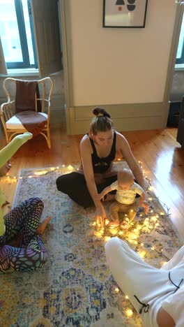 mother and baby playing with christmas lights in a living room