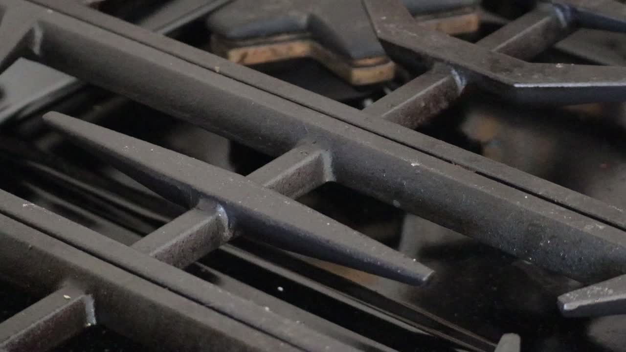 A close up of a tray of freshly baked Christmas cookies, covered in sprinkles, being placed on the stove top to cool