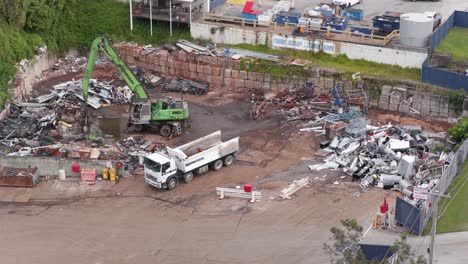 drone footage captures a truck and machinery sorting metal scrap in a gold coast junkyard under daylight