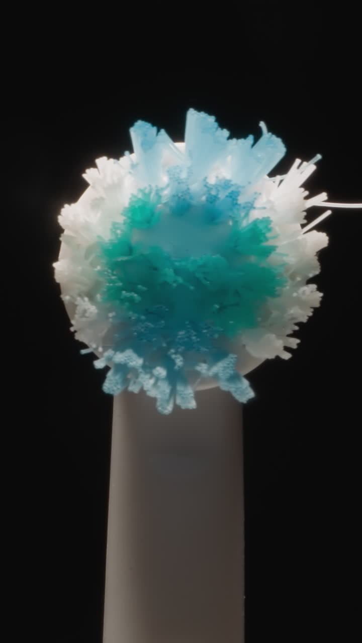 Tip of used electric toothbrush with colorful hard bristle on black background. Modern brush for professional oral hygiene at studio light macro