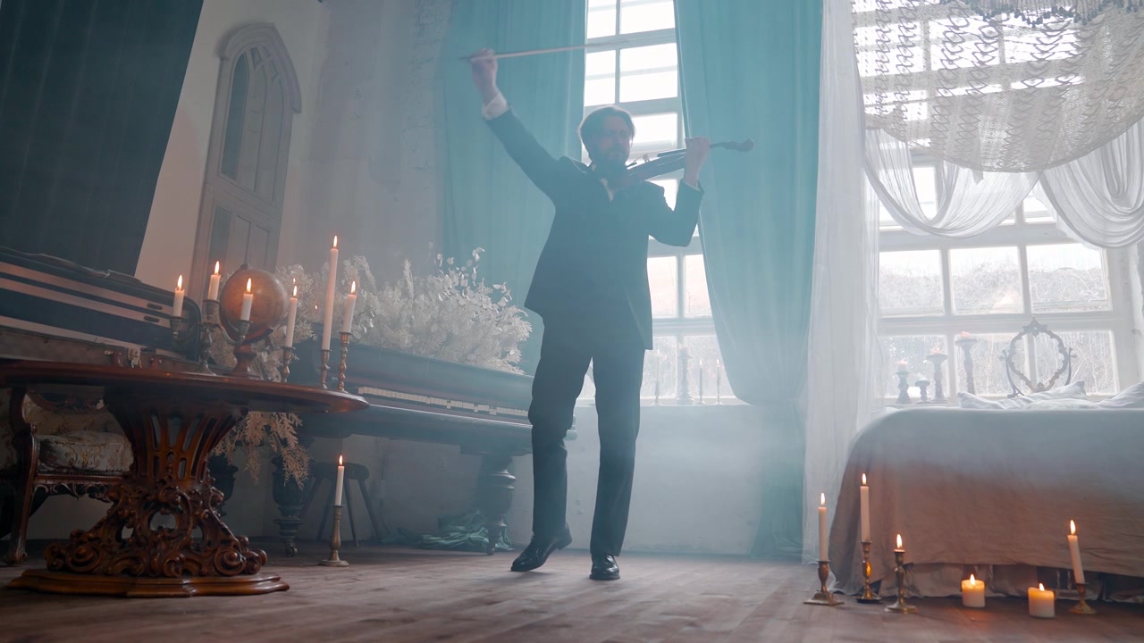 Elegant mand spiller violin i et stearinlysbelyst vintage rum.