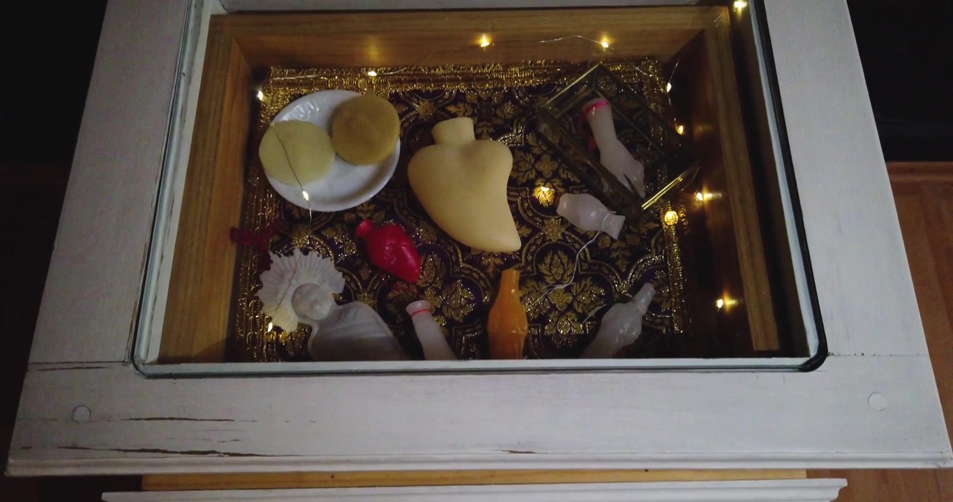 Downward shot of various types of wax figures displayed in a glass case in an exhibition hall in Mexico City