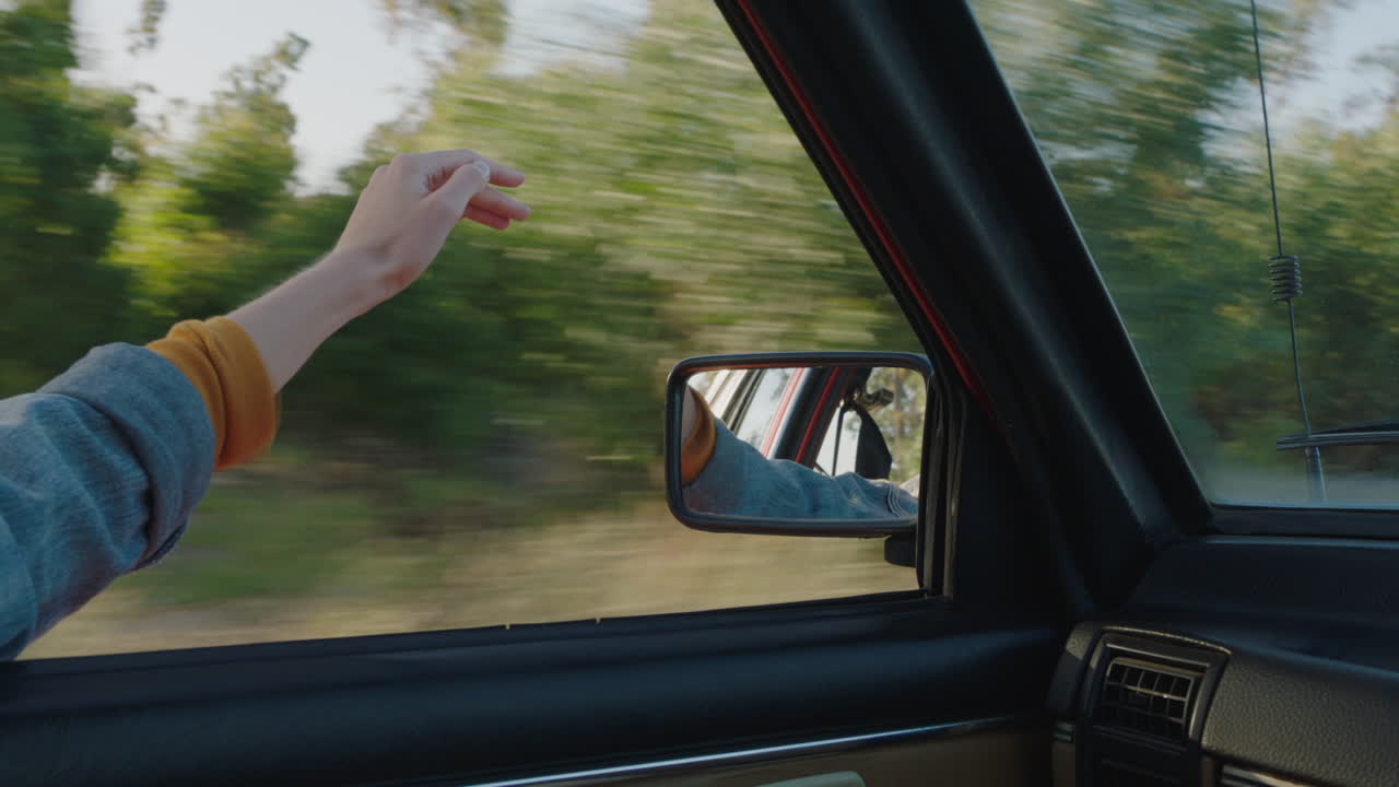 손을 내밀고 있는 여성 자동차 창문에서 손가락을 통해 바람이 불고 있는 느낌 시골에서 여행하는 여름 휴가 도로 여행 도로에서 자유를 즐기는