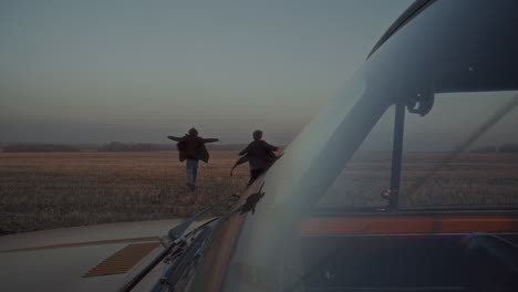 couple leaving car and running freely across field at dusk