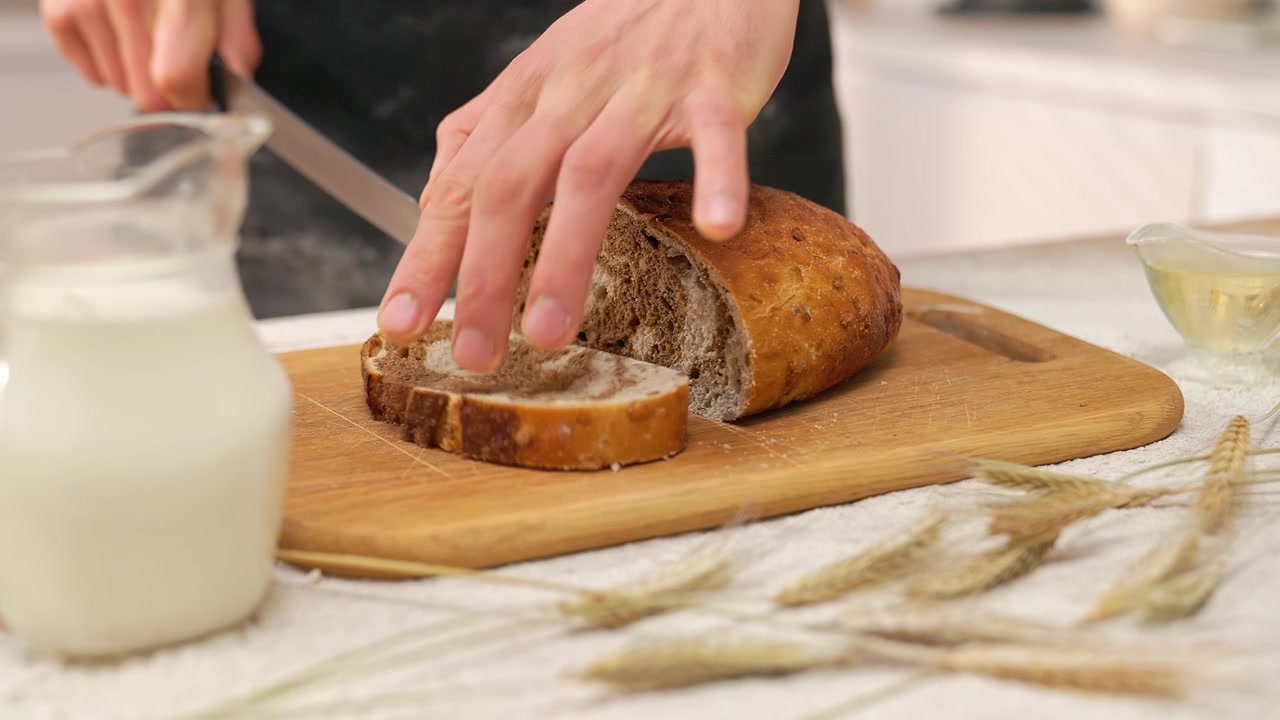 Close-up of Hands Slicing Fresh Homemade Bread on a Cutting Board