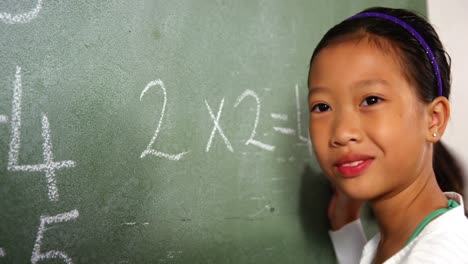 Schoolgirl-doing-mathematics-on-chalkboard-in-classroom