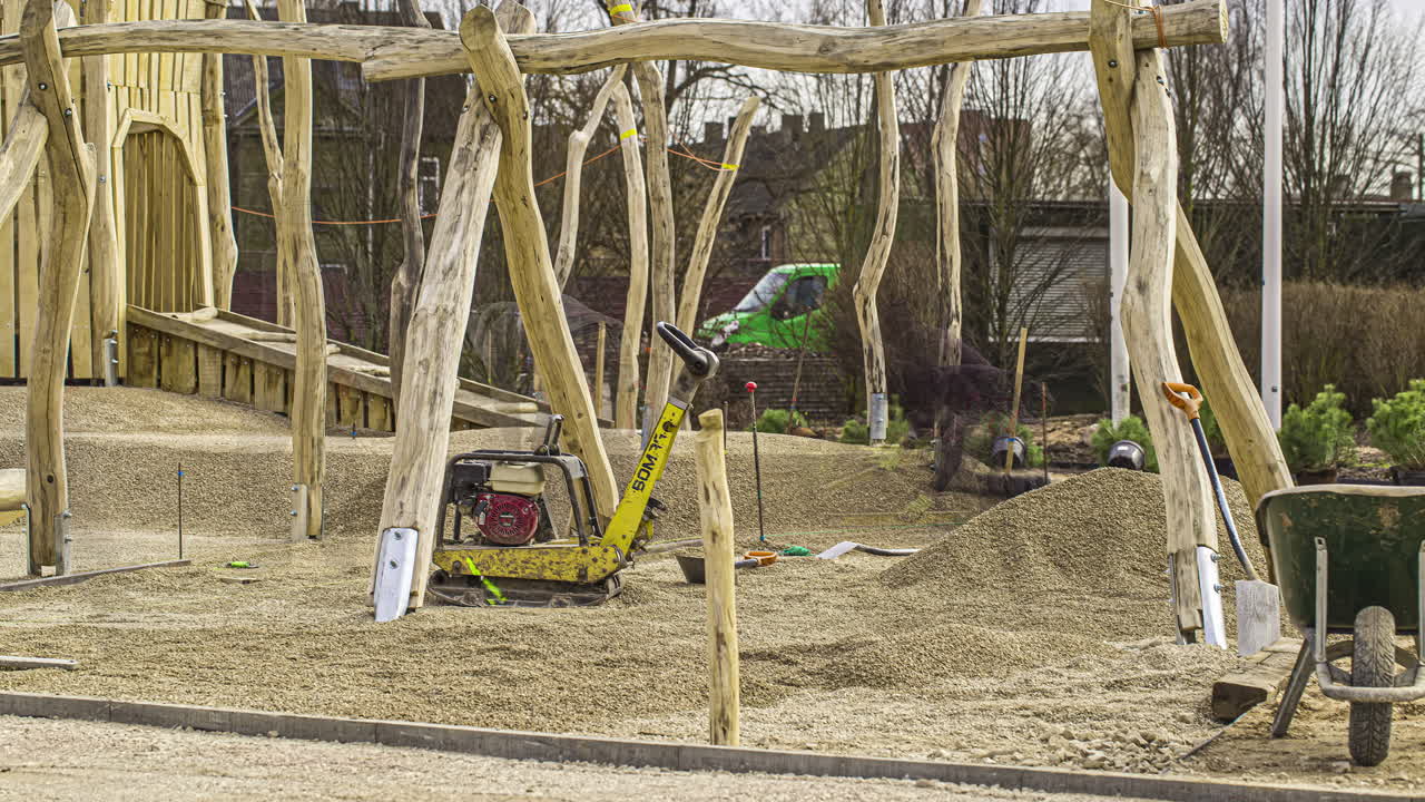 Bygningsarbejdere lægger grus på jorden på legepladsen