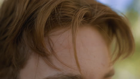 close up view of white man brown hair loosening white headband in lonely forest, blurred trees backdrop, wisps of hair framing forehead, hands pulling fabric strap under sunlight, introspective mood
