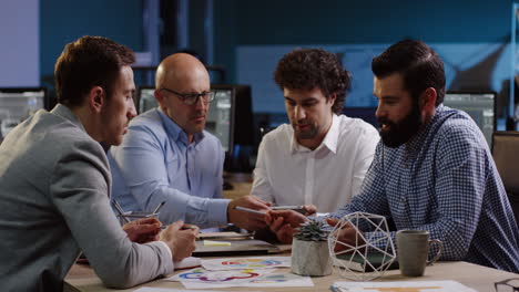 cuatro hombres de negocios sentados a la mesa y discutiendo sus planes futuros en la oficina, luego dos de ellos se dan la mano