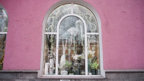 close-up view of a pink-colored house featuring an arched window with a decorative display