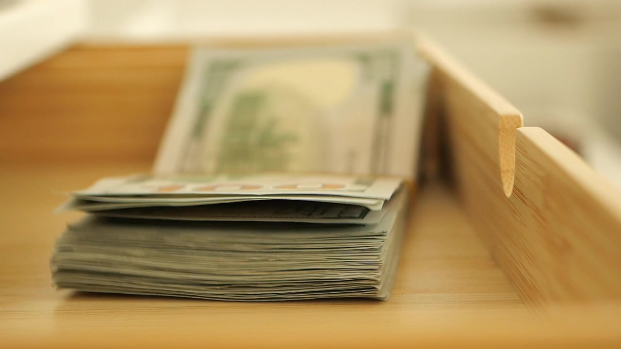 Stapel von Hundert-Dollar-Scheinen in einer Holzschublade.
