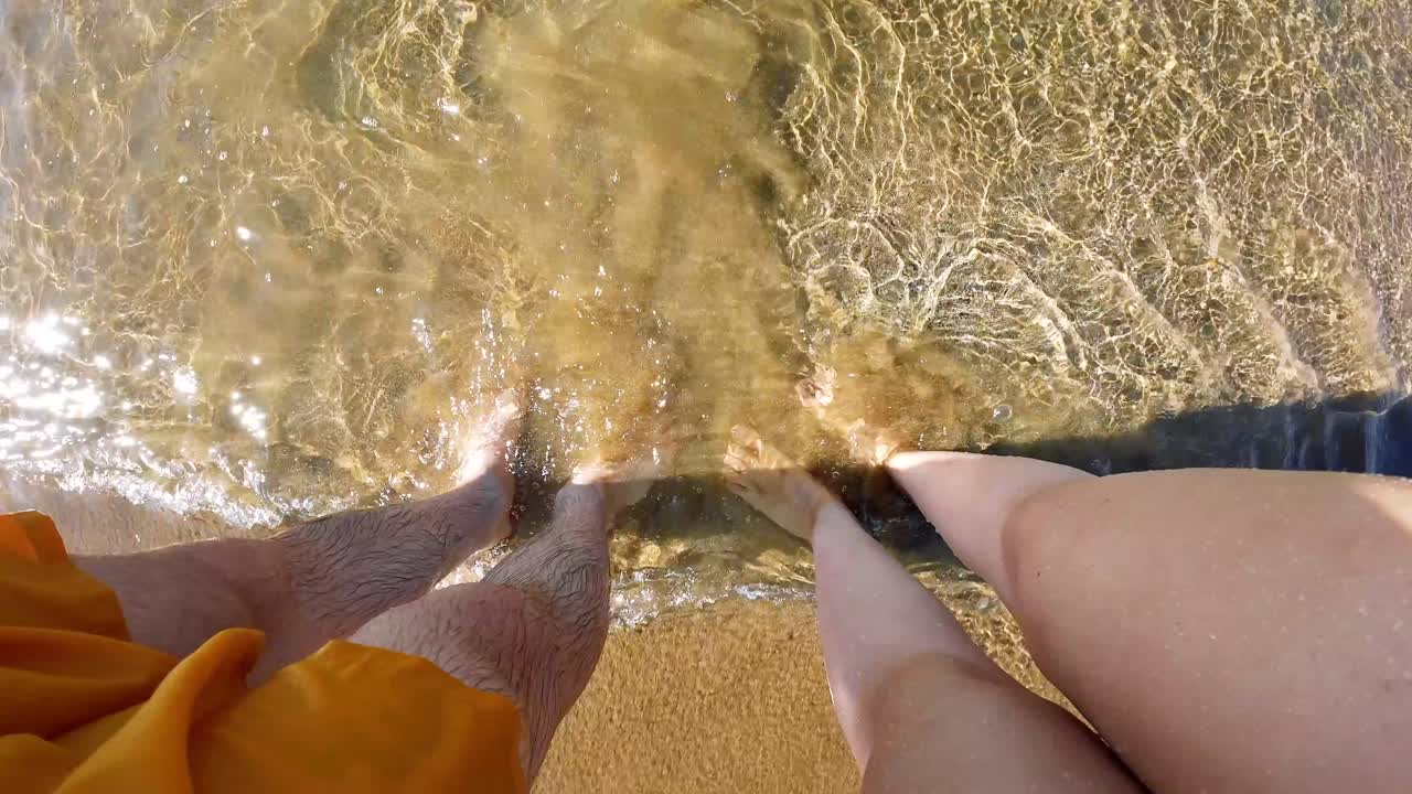 Couple with legs in sea's water at shore. Summer vacation in Turkey.