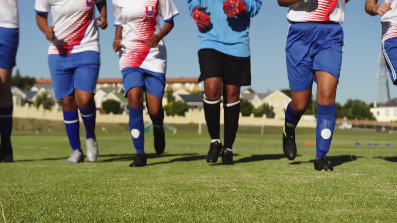 여자 축구 팀 이 축구장 에 정렬 되어 달리고 있다. 4k