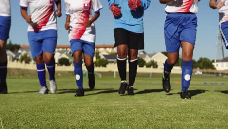 Female-soccer-team-running-aligned-on-soccer-field.-4k