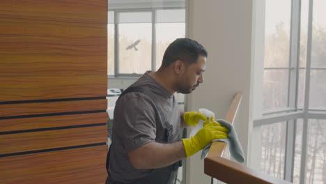 arabic cleaning man cleaning stair railing inside an office building while dancing