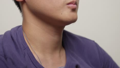 close up shot of torso of young asian man dressing, put on blue cotton t-shirt