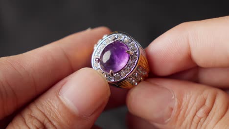 manos sosteniendo un impresionante anillo de ametista con diamantes brillantes y detalles intrincados
